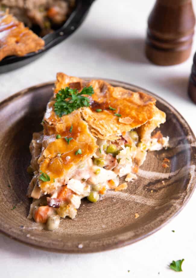 a slice of chicken bacon pot pie on a brown plate.
