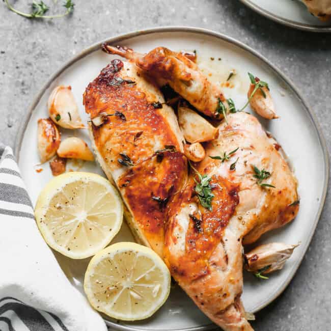 chicken under a brick on plate with lemon and parsley