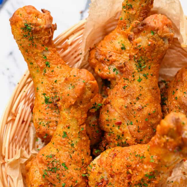 Crispy fried chicken legs in a basket on a table.