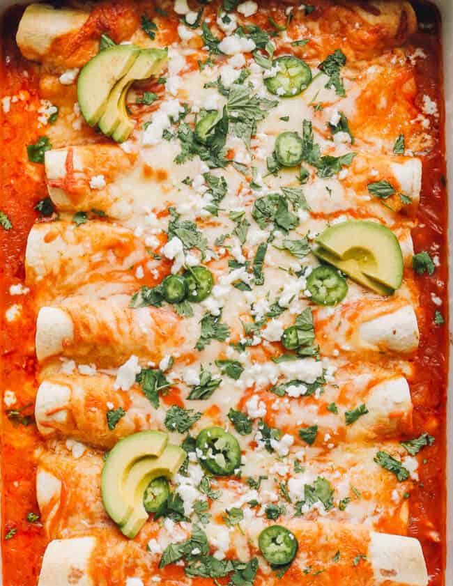 up close image of easy chicken enchiladas garnished with sour cream and cilantro