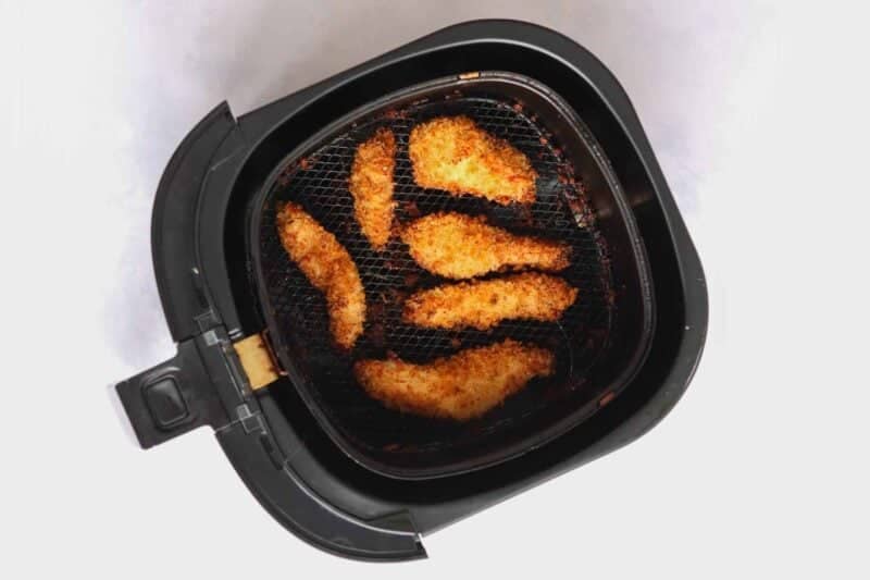 Air fryer chicken tenders on a white surface.