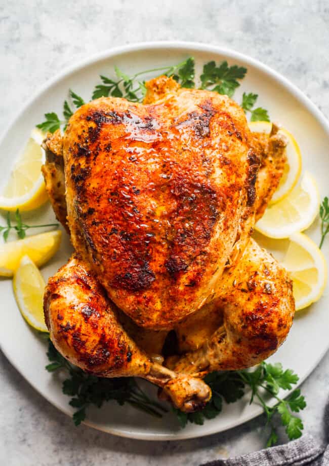 seasoned whole chicken with lemon on white plate